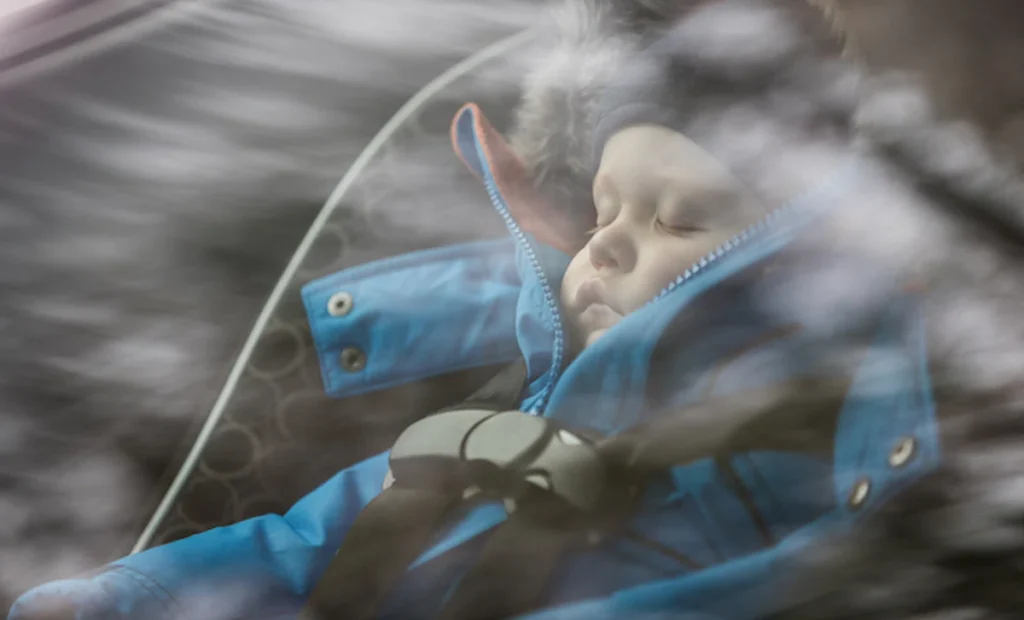 A child sleeps deeply in a car, thanks to sound insulation glass reducing outside noise and enhancing comfort.